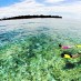 Bali, : Women snokeling over coral reef by deserted island. Banda Sea, Indonesiaa
